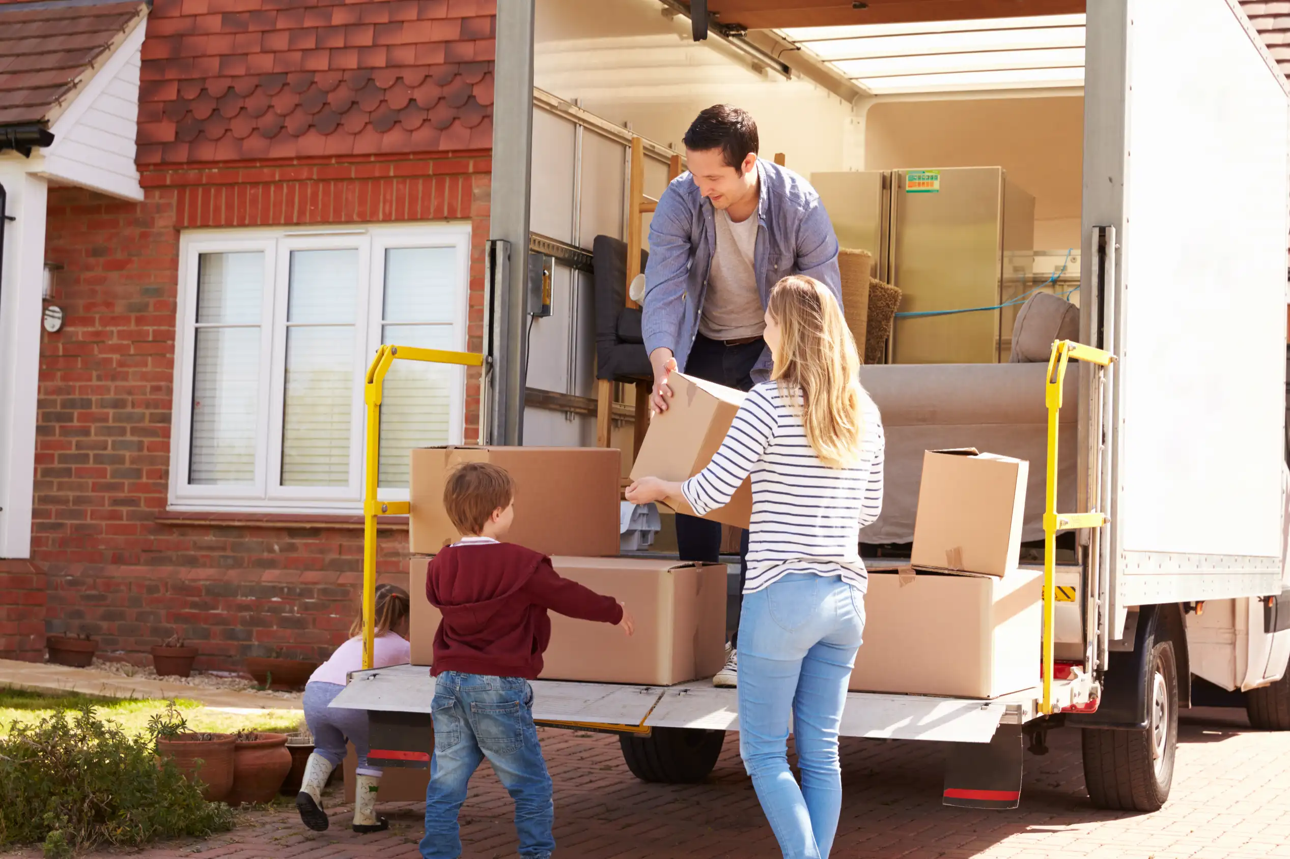 Family doing a DIY move by loading boxes into a rented truck instead of hiring home movers.